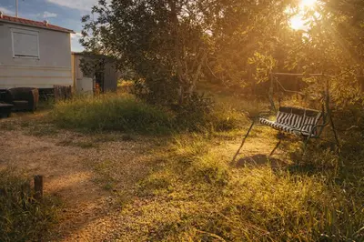 a bench sitting in the grass next to a house at A place where nothing is expected in Náquera