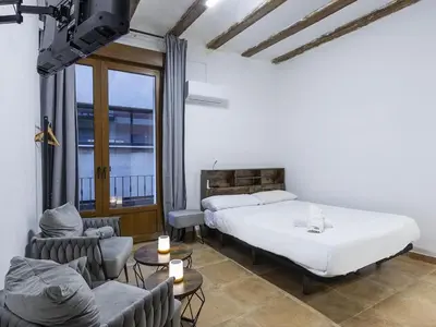a bedroom with a bed and a couch and chairs at Winahost Loft Colón in downtown Valencia in Valencia