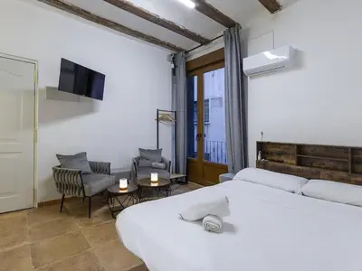 a bedroom with two beds and a tv and a chair at Winahost Loft Colón in downtown Valencia in Valencia