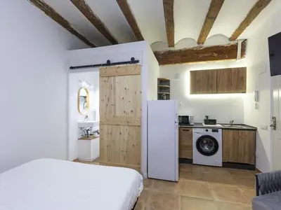a room with a bed and a kitchen with a refrigerator at Winahost Loft Colón in downtown Valencia in Valencia