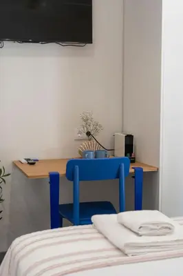 a blue chair in front of a desk with a computer at Cabanyal Rooms by VLC Host in Valencia