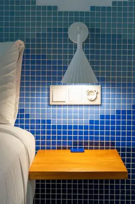 a blue tiled wall with a light above a bed at Cabanyal Rooms by VLC Host in Valencia