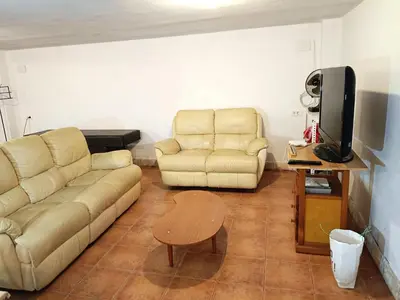 a living room with a couch and a table and a tv at La Villa Blanca in Pedralba