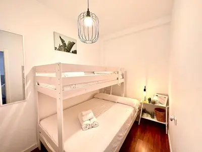 a white bunk bed in a small room with a chandelier at Padre Anton seasonal apartment in Valencia