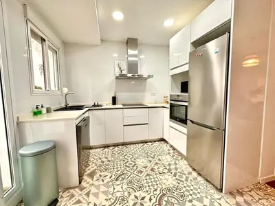 a kitchen with a stainless steel refrigerator and a tile floor at Padre Anton seasonal apartment in Valencia
