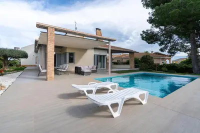 a swimming pool with two white chairs and a house at Villa Azahar - Mediterranean Retreat in Benifayó