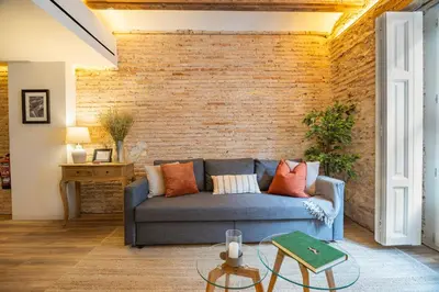 a living room with a blue couch and a brick wall at Borrull Historic Center Premiere in Valencia