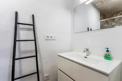 a white bathroom with a sink and a mirror at GuestReady - Traditional House near Malvarrosa in Valencia