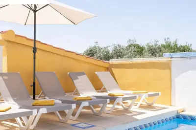 a group of chairs and an umbrella next to a pool at Tiny House Long-term en remote work near Valencia in Torrent