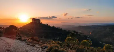 a sunset over a mountain with a tower on top at Casa de Madera I - Naturaleza y Experiencias in Bicorp