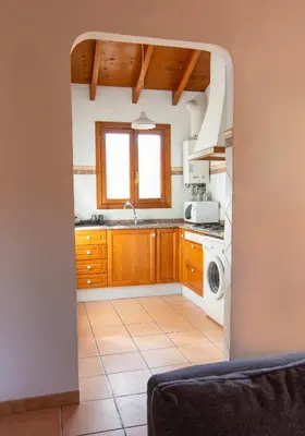 a kitchen with wooden cabinets and a washer and dryer at Casa de Madera I - Naturaleza y Experiencias in Bicorp