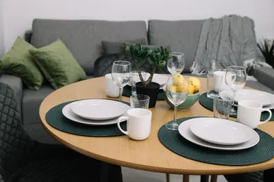 a wooden table with plates and wine glasses on it at Modern Stay Near Benicalap Park in Valencia