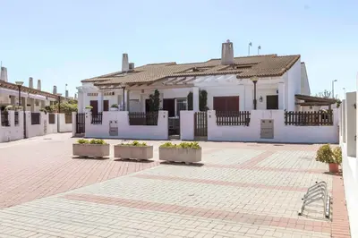 a white house with plants in pots in a courtyard at Chalet adosado junto al mar en Almarda Sagunto in Almarda