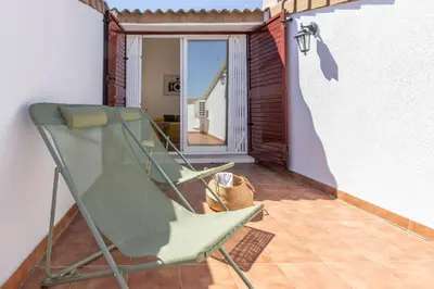 a green rocking chair on a balcony with a window at Chalet adosado junto al mar en Almarda Sagunto in Almarda
