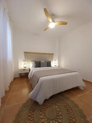 a bedroom with a large bed with a ceiling fan at Chalet adosado junto al mar en Almarda Sagunto in Almarda