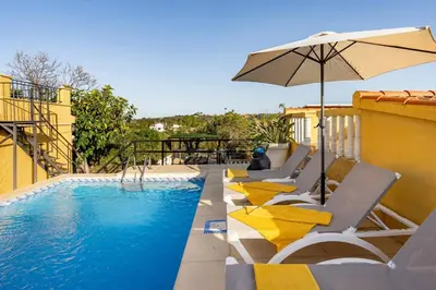 a swimming pool with lounge chairs and an umbrella at Casa Rosa Longterm Living and Workspace in Monserrat