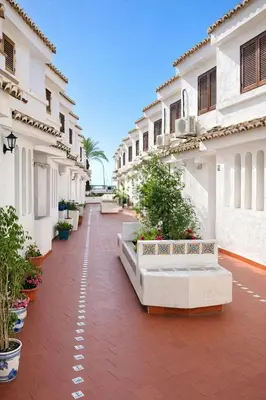 a courtyard of a white building with plants and benches at Terraced House MARIELISA in Puebla de Farnals