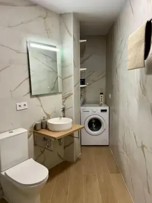 a bathroom with a toilet and a sink and a washing machine at Aqua Vida Apartments Sueca in Sueca