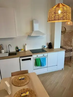 a kitchen with white cabinets and a sink and a table at Aqua Vida Apartments Sueca in Sueca