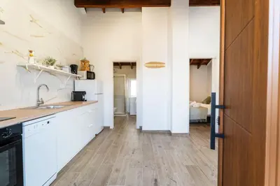a kitchen with white cabinets and a wooden floor at Pinedo Playa Rustico in Valencia