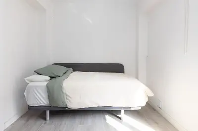 a bed in a bedroom with white walls and wooden floors at Mislata Apartment in Valencia