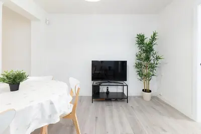 a white living room with a table and a tv at Mislata Apartment in Valencia