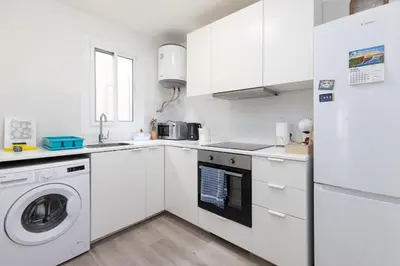 a white kitchen with a washing machine and a refrigerator at Mislata Apartment in Valencia