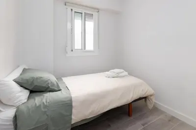 a bed in a white room with a window at Mislata Apartment in Valencia