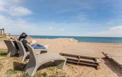 a woman sitting on a bench on the beach at Lovely Apartment In Tavernes De La Valldig in Tavernes de Valldigna