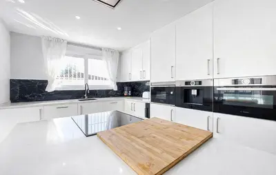 a kitchen with white cabinets and a wooden table at Awesome Home In Olocau in Olocau