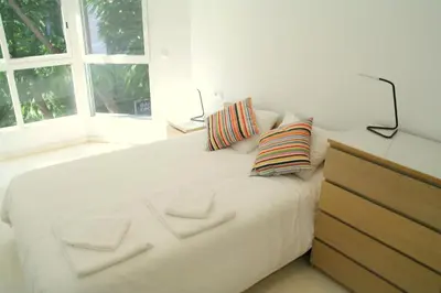 a white bed with pillows and a dresser in a bedroom at Mestalla Silence in Valencia