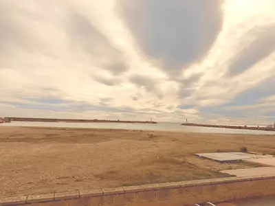 a beach with the ocean and a cloudy sky at Puerto Beach House in Puebla de Farnals