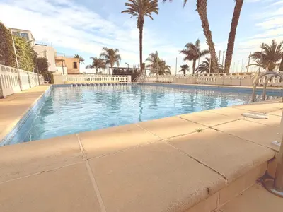 a large swimming pool with palm trees in the background at Puerto Beach House in Puebla de Farnals