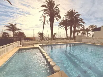 a large swimming pool with palm trees in the background at Puerto Beach House in Puebla de Farnals