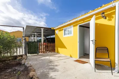 a yellow house with a chair in a driveway at Tiny House Long-term remote work near Valencia in Monserrat