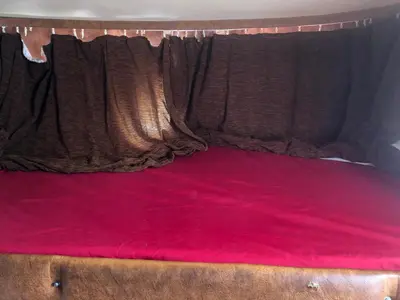 a bed with red sheets and a brown curtain at Autocaravana in Port Saplaya