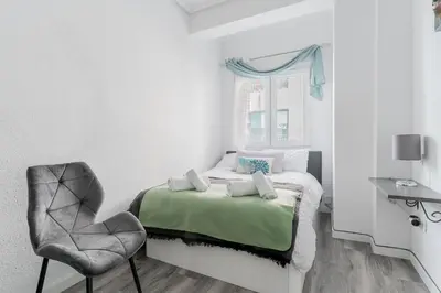 a white bedroom with a bed and a chair at Modern 2BR Apartment with Terrace in Valencia in Valencia