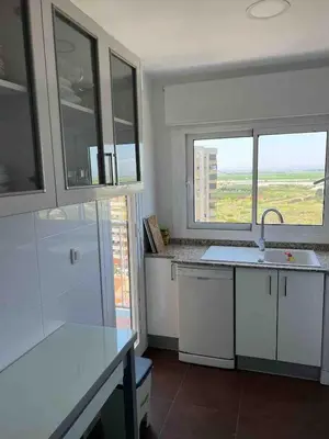a kitchen with white cabinets and a large window at Triton in Mareny Blau
