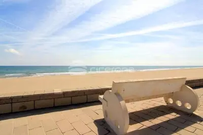 a bench sitting on a wall near the beach at Triton in Mareny Blau