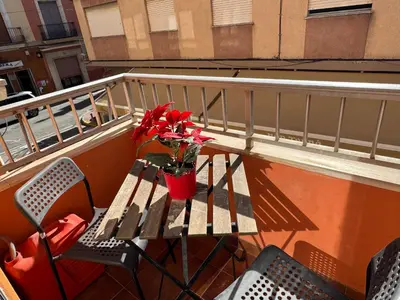 a table and chairs on a balcony with red flowers at Albalat Centro in Albalat de la Ribera