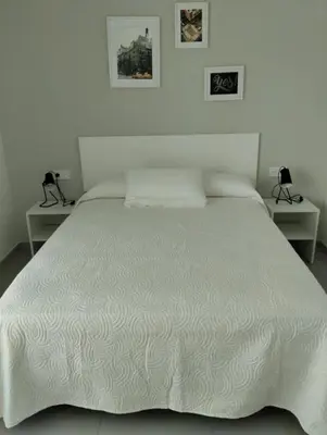 a bedroom with a white bed with two tables at Iberflat Apartamentos Alfabega in Paterna