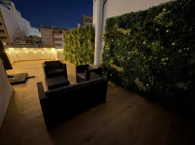 a rooftop patio with furniture and a green hedge at Ático Premium Centro de Tavernes, Terraza & BBQ in Tavernes de Valldigna