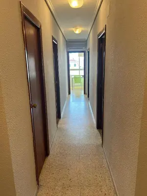 a hallway with two doors and a room with a table at Apartamento Perellonet Mascaró in El Perellonet