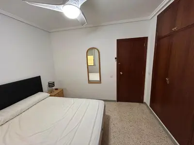a bedroom with a bed with a ceiling fan and a door at Apartamento Perellonet Mascaró in El Perellonet