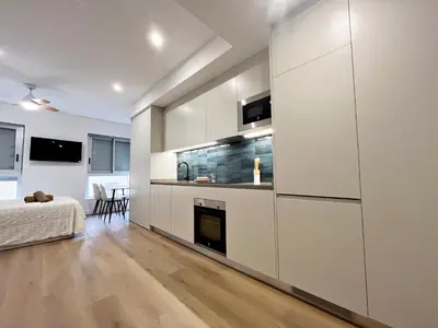 a kitchen with white cabinets and a fireplace at Loft en el Centro De Valencia Botánico 2 in Valencia
