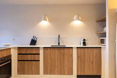 a kitchen with wooden cabinets and two lights on the wall at VLC Host - Reina 166 B in Valencia