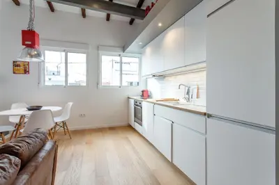 a kitchen with white cabinets and a table and a couch at Apartment Ruzafa Puerto Rico in Valencia