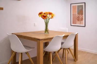 a vase of flowers on a wooden table with white chairs at Roig Arena Suite Garden N9 in Valencia