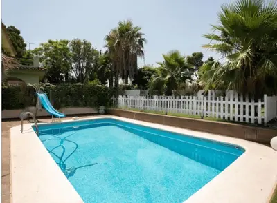 a swimming pool with a slide in front of a white fence at EXCLUSIVA CASA INDEPENDIENTE 16 ppl in Torrent