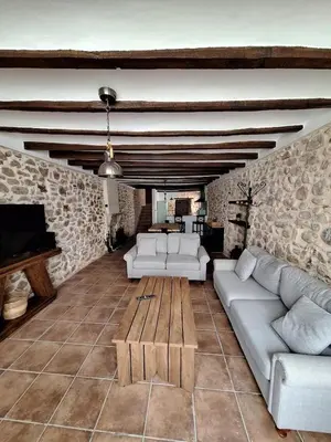 a living room with white furniture and a stone wall at Casa Trilles in Azuébar